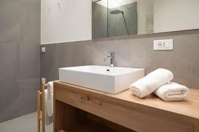 a bathroom with a white sink and a mirror at Villa Rosengarten Guesthouse in Merano