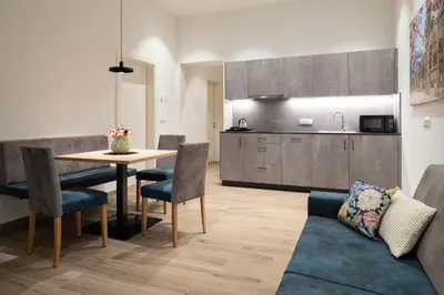 a living room with a table and chairs and a kitchen at Villa Rosengarten Guesthouse in Merano