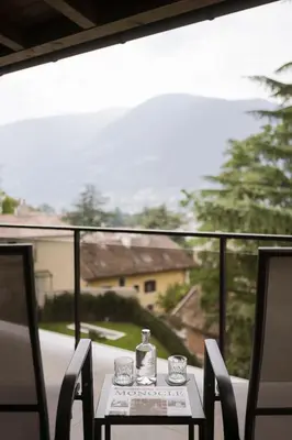 a table with glasses and a bottle on a balcony at Villa Rosengarten Guesthouse in Merano