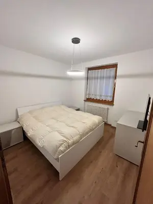 a white bedroom with a bed and a window at Primule 2 Cavareno in Cavareno