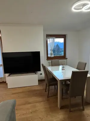 a living room with a table and a large television at Primule 2 Cavareno in Cavareno