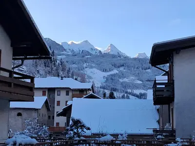 a view of a town with snow covered buildings and mountains at La Casetta del Cervo a Fiori in Predazzo