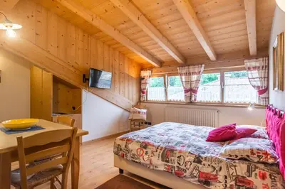 a bedroom with a bed and a table in a room at Holiday Apartments Val Moena 2 in Cavalese