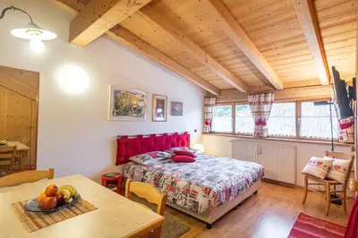 a bedroom with a red bed and a table at Holiday Apartments Val Moena 2 in Cavalese