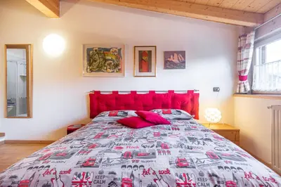 a bedroom with a large bed with a red headboard at Holiday Apartments Val Moena 2 in Cavalese