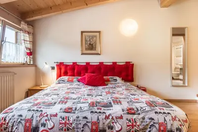 a bedroom with a bed with a red head board at Holiday Apartments Val Moena 2 in Cavalese
