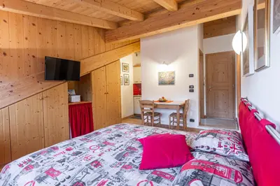 a bedroom with a bed with pink pillows and a table at Holiday Apartments Val Moena 2 in Cavalese