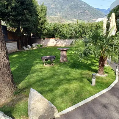 a fake cow sitting on the grass in a yard at Hotel Angerer in Bressanone