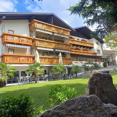 a resort with a large building with tables and chairs at Hotel Angerer in Bressanone
