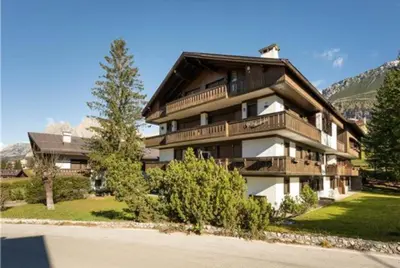 a large wooden house with mountains in the background at ca peziè in Zuel