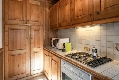 a kitchen with wooden cabinets and a stove top oven at ca peziè in Zuel