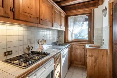 a kitchen with wooden cabinets and a stove top oven at ca peziè in Zuel