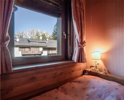 a bedroom with a window and a bed and a lamp at ca peziè in Zuel