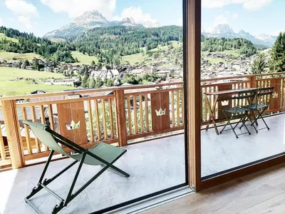 a balcony with two chairs and a table and mountains at Villa Re Laurino Suite Tra le nuvole in Moena