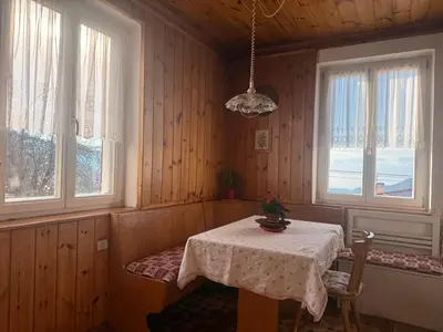 a dining room with a table and two windows at Casa Montana & Zampette in Fondo