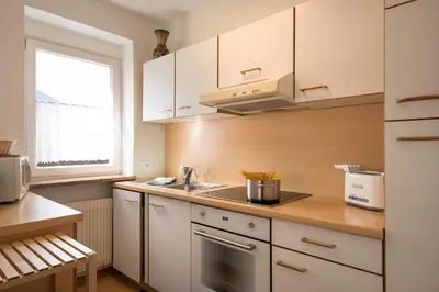 a kitchen with white cabinets and a sink and a window at Residence Sisi in Ortisei