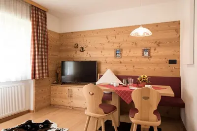 a dining room with a table and chairs and a television at Residence Sisi in Ortisei