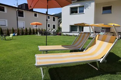 two lounge chairs and an umbrella in a yard at Residence Sisi in Ortisei
