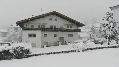 a house covered in snow in a yard at Residence Sisi in Ortisei
