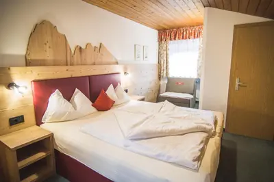 a bedroom with a large white bed with a wooden headboard at Residence Sisi in Ortisei