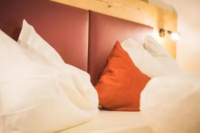a bed with white and red pillows on it at Residence Sisi in Ortisei