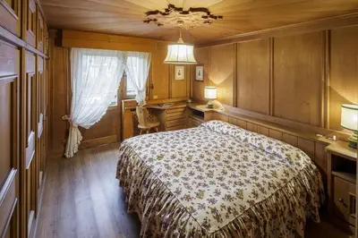 a bedroom with a bed and a desk and a window at Villa Riadezeto - Stayincortina in Cortina dʼAmpezzo