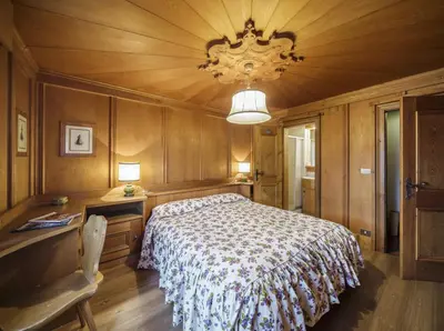 a bedroom with a bed and a table and a chandelier at Villa Riadezeto - Stayincortina in Cortina dʼAmpezzo
