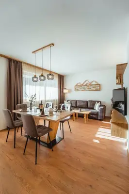 a living room with a table and chairs and a couch at Nature Apartments Stifter in Villabassa