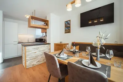 a dining room with a table and chairs and a kitchen at Nature Apartments Stifter in Villabassa