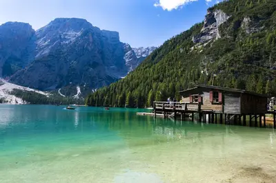 a lake with a wooden house in the middle of a mountain at Nature Apartments Stifter in Villabassa