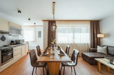 a kitchen and living room with a table and chairs at Nature Apartments Stifter in Villabassa