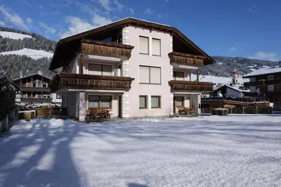a house in the snow in front of a mountain at Nature Apartments Stifter in Villabassa