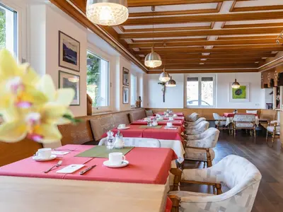 a restaurant with red tables and chairs and windows at B&B Chalet Andy in Schenna