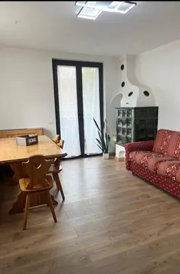 a living room with a red couch and a table at Appartamento Buca Neve - Tesero in Tesero