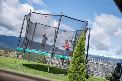 two children are playing on a trampoline at Haus Pötzes in Castelrotto