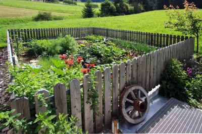 a garden with a wooden fence and flowers at Haus Pötzes in Castelrotto
