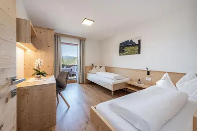 a hotel room with two beds and a desk and a room at Haus Pötzes in Castelrotto