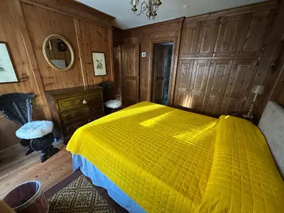 a bedroom with a yellow bed and wooden walls at Appartamento 3 camere pieno centro di Cortina in Cortina dʼAmpezzo