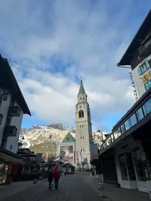 a building with a clock tower on a street at Appartamento 3 camere pieno centro di Cortina in Cortina dʼAmpezzo