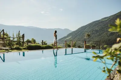 a person standing on the edge of a swimming pool at Niedermair Nature Retreat in Parcines
