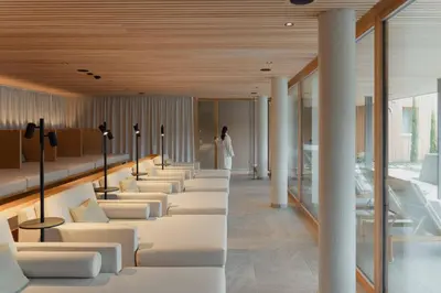 a room with white couches and a woman in the background at Niedermair Nature Retreat in Parcines