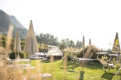 a group of tables and chairs with umbrellas in the grass at Niedermair Nature Retreat in Parcines