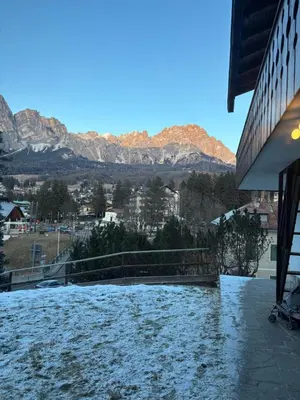 a view of a snow covered building with mountains in the background at Ca' Scalinatella in Cortina dʼAmpezzo