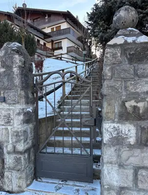 a gate leading up to a building with stairs at Ca' Scalinatella in Cortina dʼAmpezzo