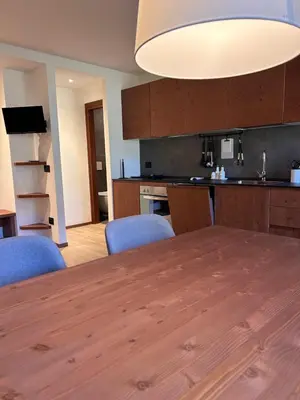 a kitchen with a wooden table and blue chairs at Mazzantini appartamento vacanza San Martino di Castrozza in San Martino di Castrozza