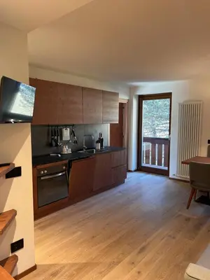 a large kitchen with wooden floors and a large window at Mazzantini appartamento vacanza San Martino di Castrozza in San Martino di Castrozza