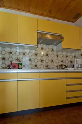 a kitchen with yellow cabinets and a stove at Apartment mit privatem Balkon by Interhome in Ortisei