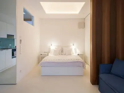 a bedroom with a white bed and a blue couch at Holiday Home Mirror House Nord by Interhome in Bolzano
