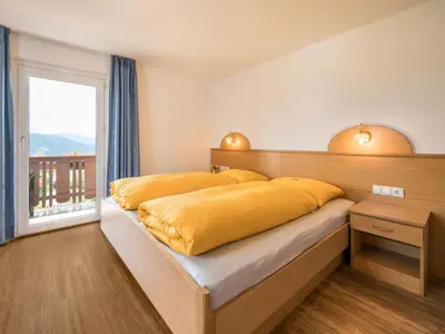 a bedroom with a large yellow bed with a window at Apartment Haus Adler by Interhome in Maranza