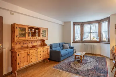 a living room with a blue couch and a wooden cabinet at Casa Tre Corone, sulla strada per Cortina in Borca di Cadore